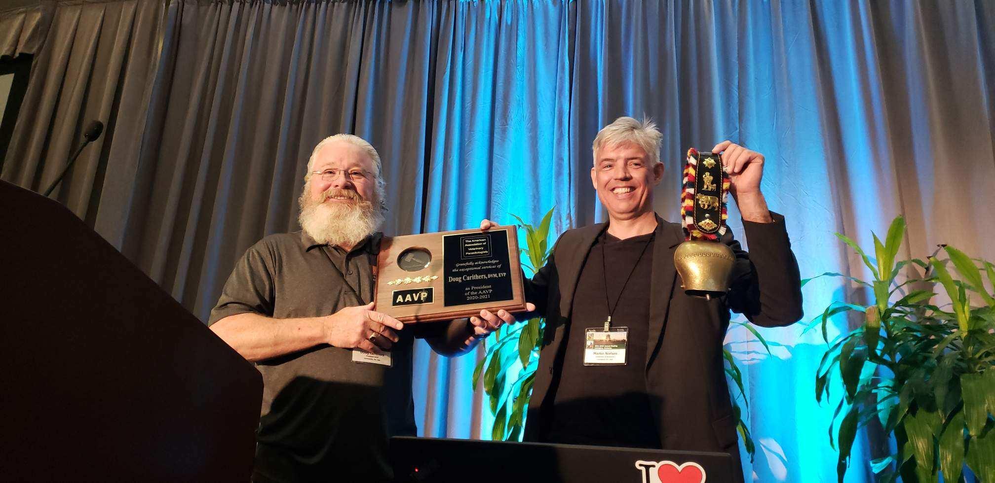 Martin Nielsen accepts the handoff of the presidency cowbell from predecessor